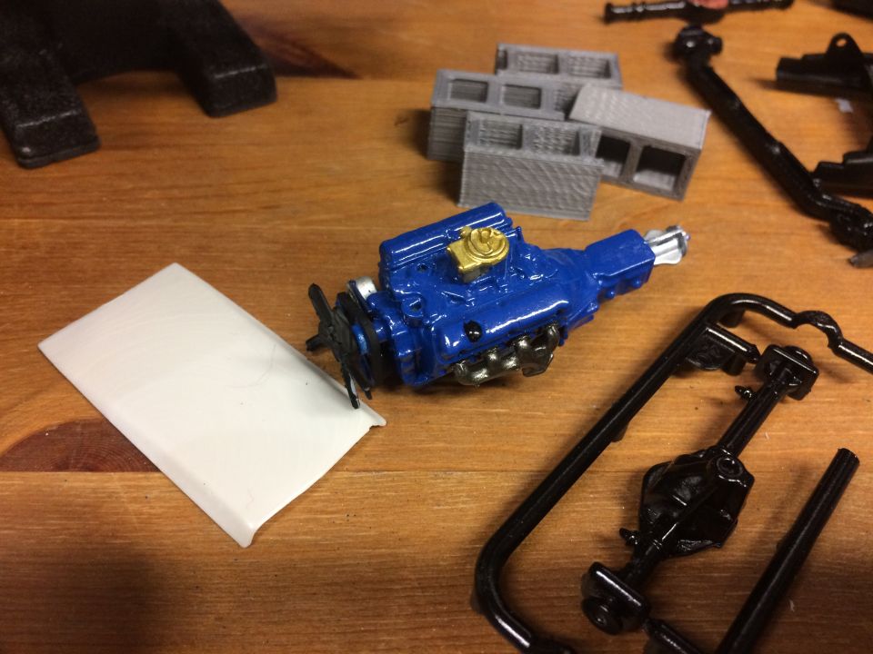 Model engine and car parts on a wooden surface