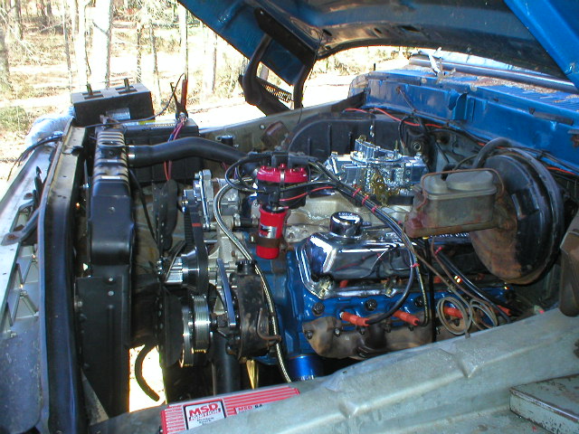 Blue V8 engine bay with red distributor cap, exposed four-barrel carb and an MSD ignition box
