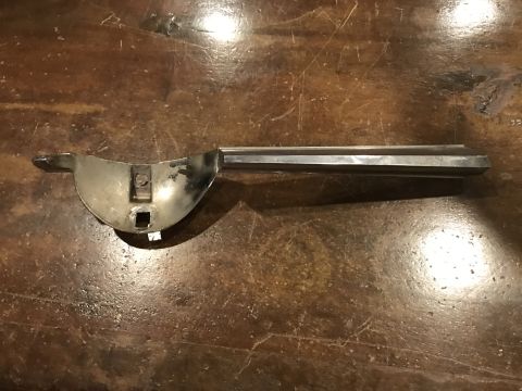1965 Ford Mustang - A chrome-plated metal part, possibly a car door handle or trim piece, is shown lying on a wooden surface. The object has a curved section a…