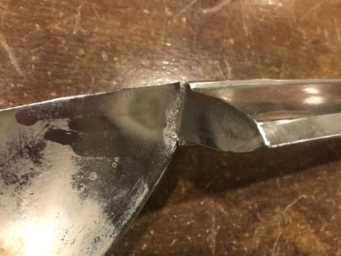 1965 Ford Mustang - Close-up view of a damaged chrome-plated metal part, possibly a vehicle trim piece, showing a break or separation with rough edges and some…