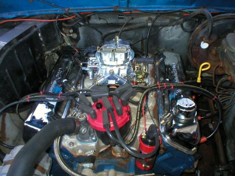 1978 Ford Bronco - Overhead view into the engine bay of a blue truck showing a V8 with a polished four-barrel carburetor on an aluminum intake, a red HEI-styl…