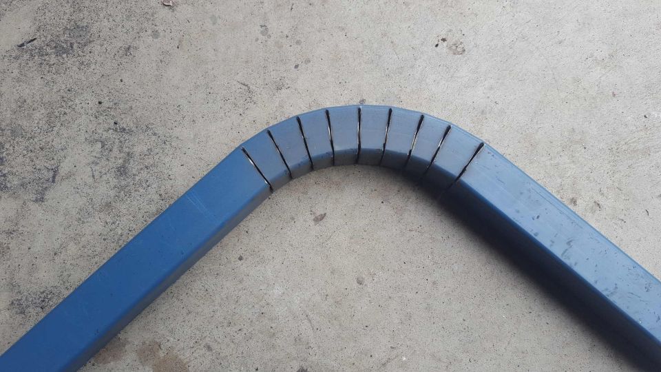 Blue metal tube bent and segmented on concrete