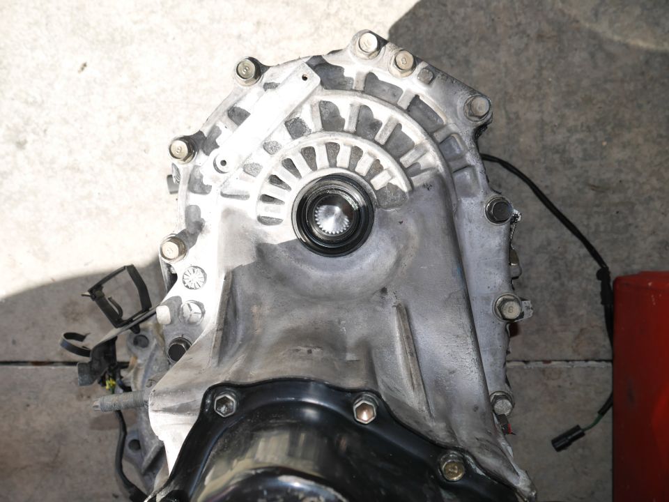 Overhead view of a silver transmission assembly with visible bolts and input shaft.