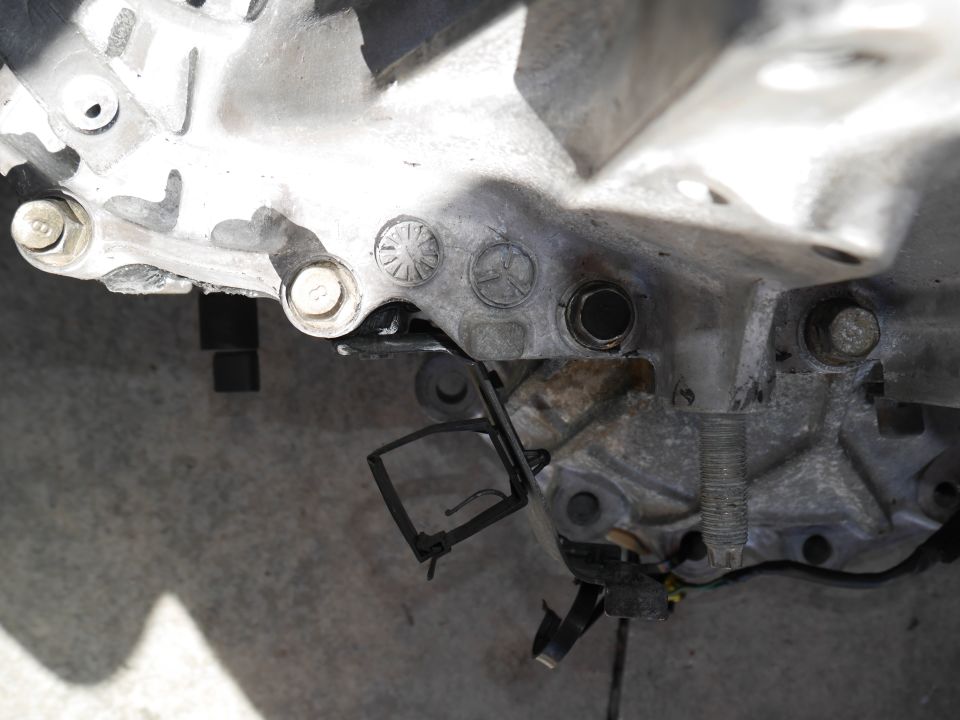 Close-up of vehicle transmission housing with bolts and bracket.