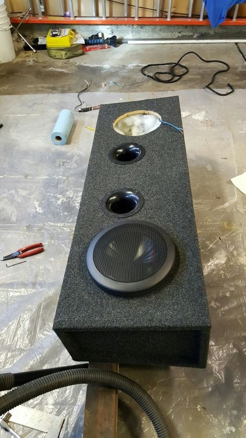 1996 Ford Bronco - A custom-built speaker enclosure with three openings, one for a speaker and two for ports, is shown on a concrete floor. The enclosure is c…