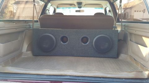 1996 Ford Bronco - The rear cargo area of a 1996 Ford Bronco is shown with a large, gray carpeted subwoofer box installed. The subwoofer box contains two larg…