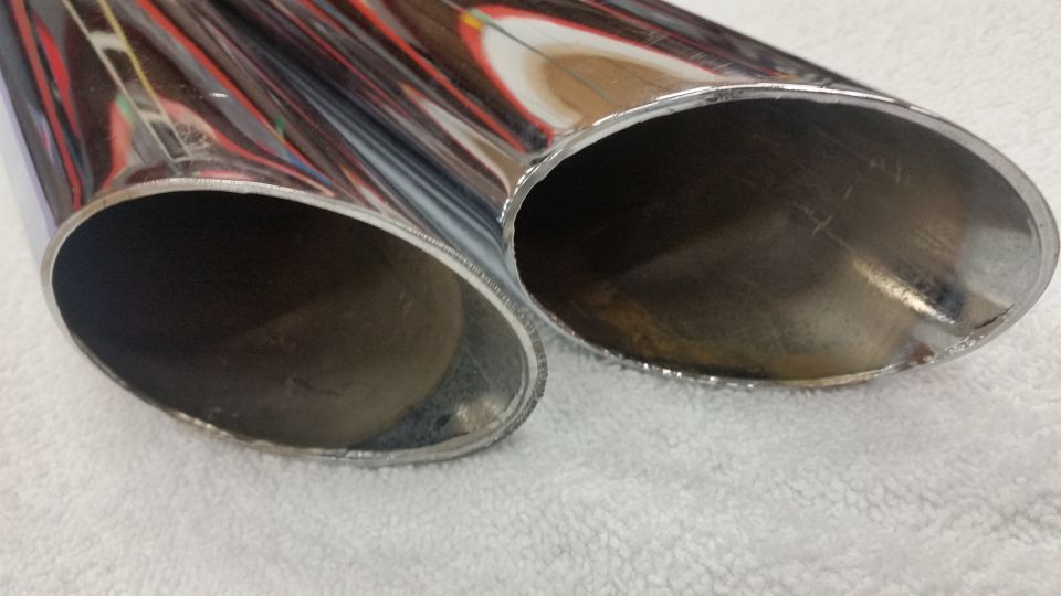 Two chrome exhaust pipes cut at an angle, showing the interior and exterior.