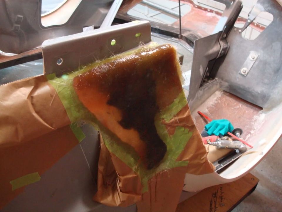 Fiberglass repair in progress on a vehicle interior, with tools and masking tape visible.