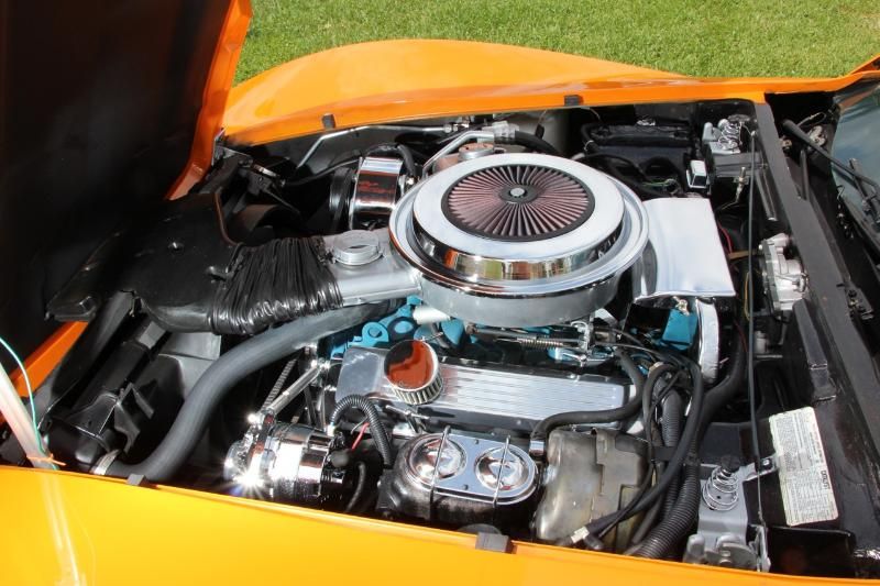 Orange vehicle engine bay with chrome air cleaner and polished engine parts.