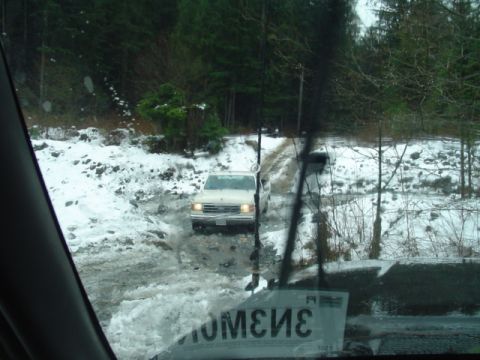 1993 Ford Bronco - A white 1992 Ford Bronco navigates a challenging snowy and muddy terrain.