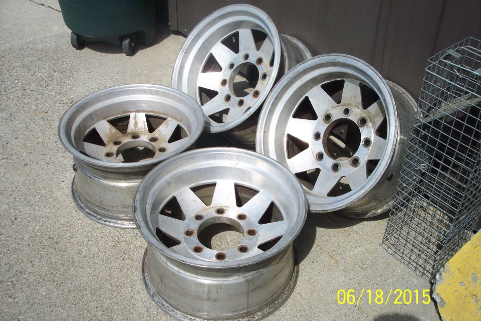 Five aluminum alloy wheels on a concrete surface.