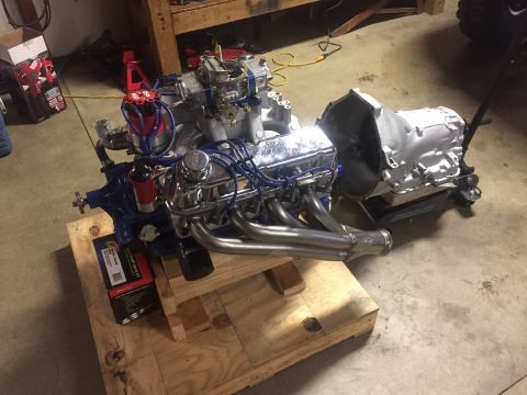 1982 Ford Bronco - A V8 engine and automatic transmission assembly is mounted on a wooden pallet, with exhaust headers and a distributor visible. The engine i…