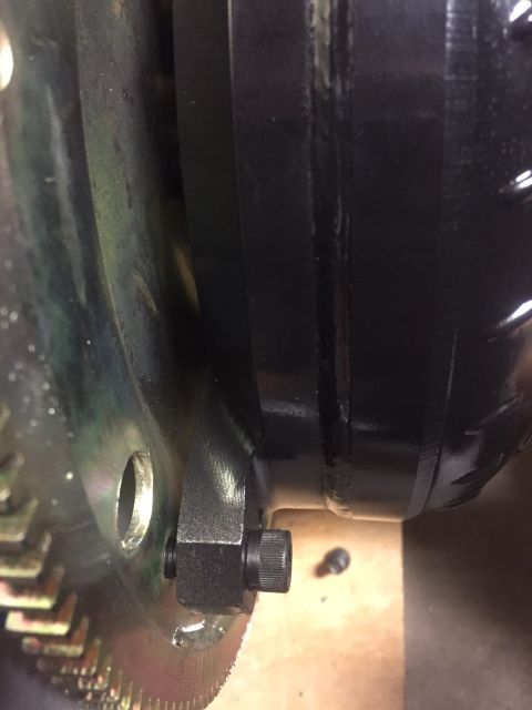 1982 Ford Bronco - A close-up view shows a black bolt securing a metal bracket to a toothed metal disc, likely part of a vehicle's drivetrain or engine assemb…