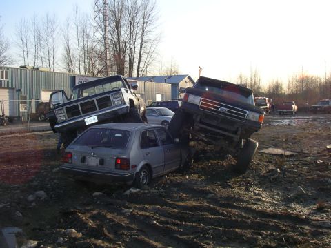 1990 Ford F-150 - A scene of vehicular destruction shows two pickup trucks on top of a small car.
