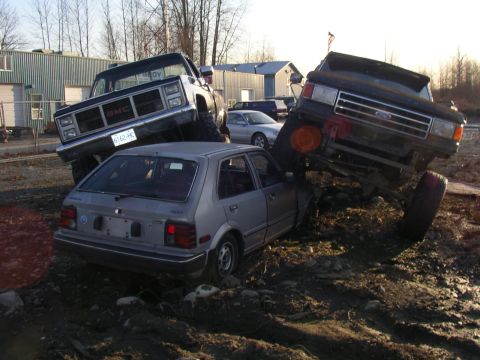 1990 Ford F-150 - Off-road vehicles are shown in a challenging muddy terrain, with one truck on top of a car.