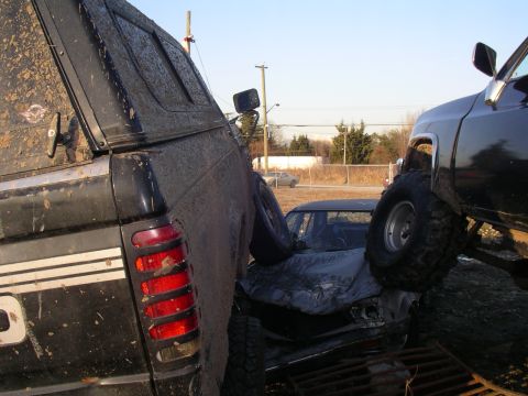 1990 Ford F-150 - A scene of vehicular destruction with multiple trucks and a severely damaged car.