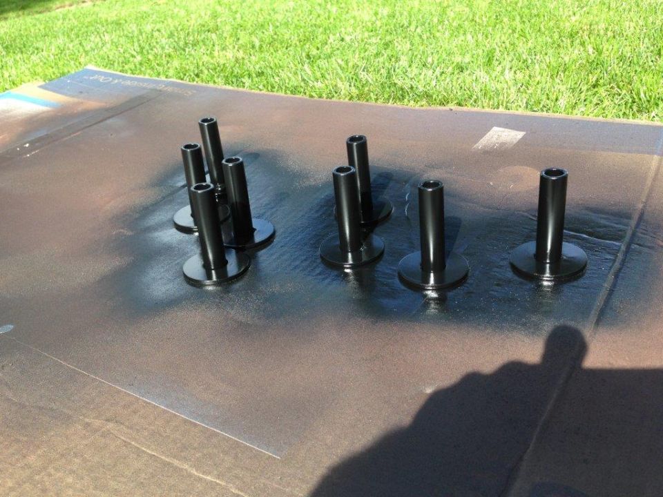 Black metal parts on a brown surface with grass in the background.
