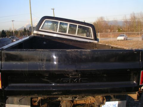 1990 Ford F-150 - This GMC pickup truck, likely from the 1980s, is seen from the rear with a camper shell installed.