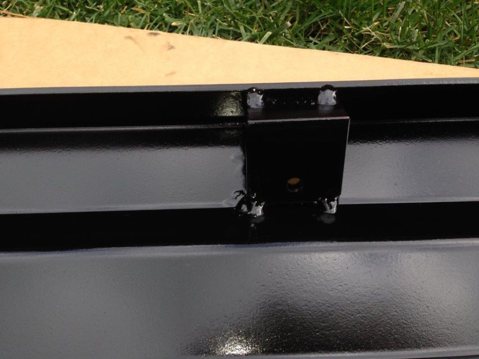 Black metal bracket welded onto a black metal frame.