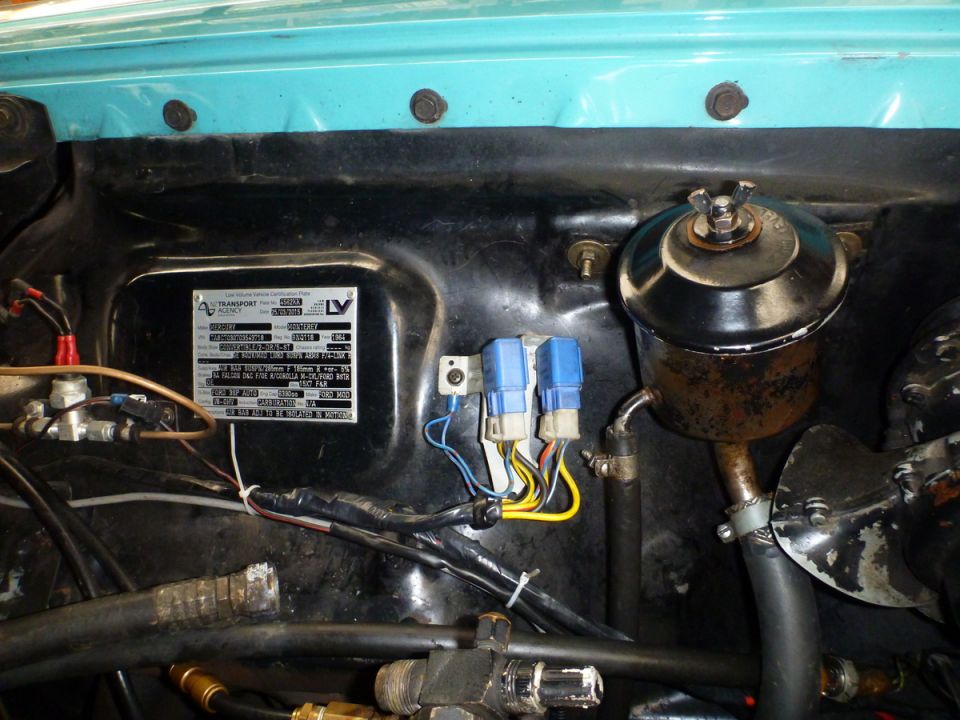 Engine bay of a 1964 Mercury Monterey with certification plate and engine components.