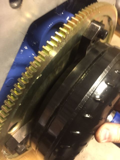1982 Ford Bronco - A close-up view shows a golden gear with black teeth meshing with a black component. A blue metal piece is visible in the background.