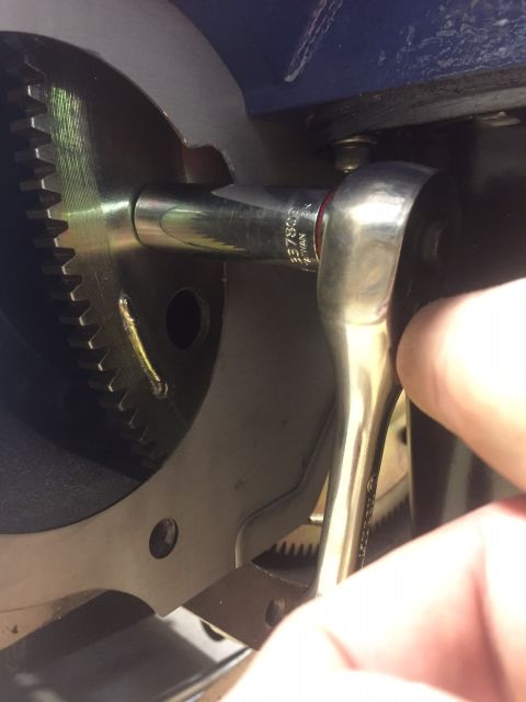 1982 Ford Bronco - A hand uses a socket wrench to tighten a bolt on a metal component with visible gear teeth, likely part of a vehicle's drivetrain or transm…