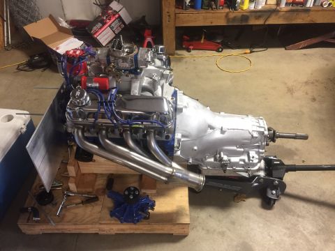 1982 Ford Bronco - A silver V8 engine and transmission assembly is mounted on wooden blocks and a jack. The engine features chrome valve covers, a chrome air…