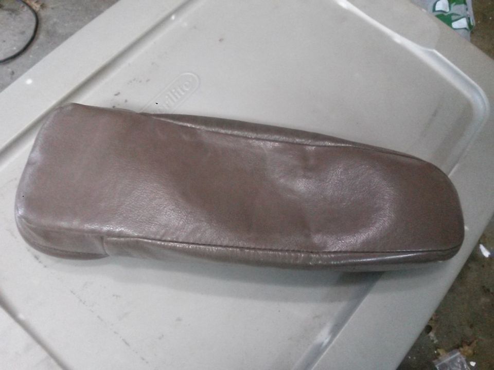 Brown leather vehicle armrest cover on a plastic bin lid