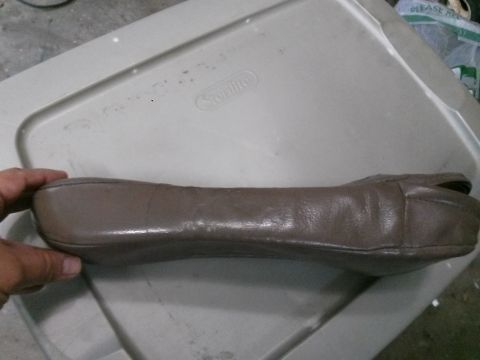 1996 Ford Bronco - A hand is holding a brown leather shoe against a grey plastic storage bin.