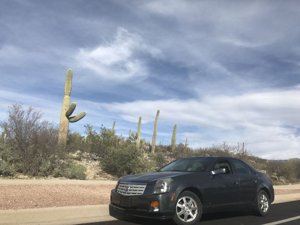 2007 Cadillac CTS sedan parked roadside in a desert with saguaro cacti.