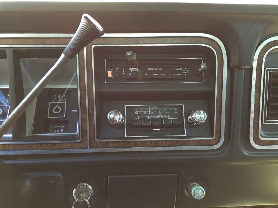 1979 Ford Bronco interior dashboard with steering column, radio, and key in ignition.