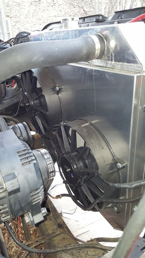 1978 Ford Bronco - Close-up of an engine bay showing an aluminum radiator, dual electric fans, and an alternator with a labeled belt.