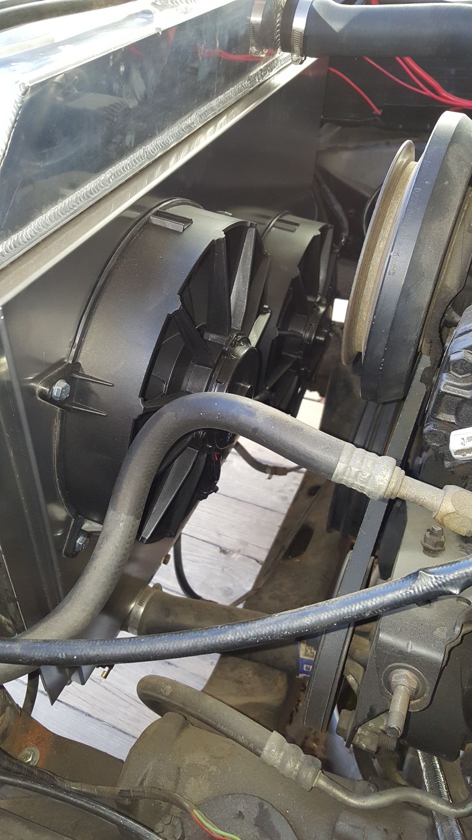 Close-up of dual electric cooling fans mounted to an aluminum radiator with hoses and belts visible