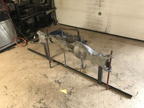 1996 Ford Bronco - Axle assembly is set up on a stand for modification or repair in a garage setting.