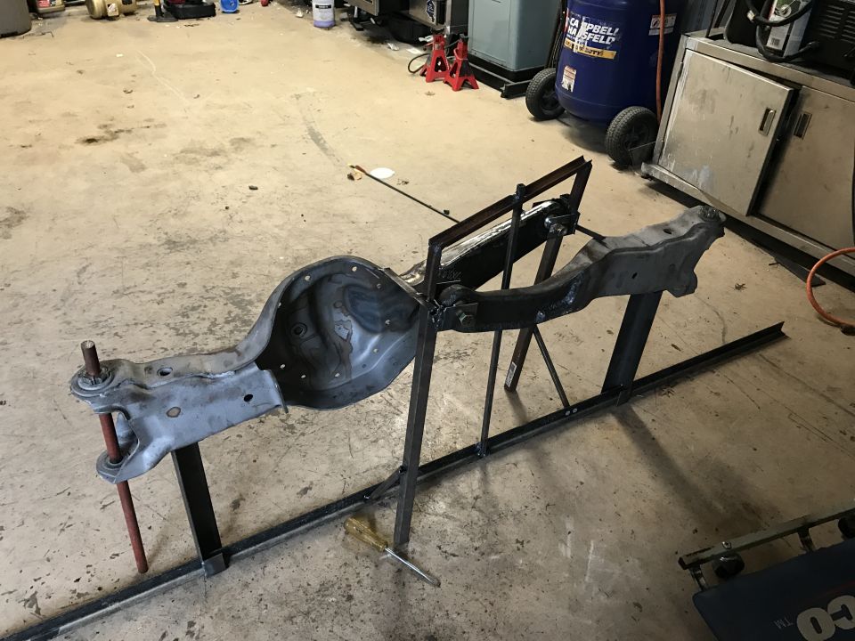 Vehicle axle assembly mounted on a metal stand in a garage
