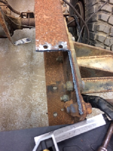 1993 Ford Bronco - Close-up of a heavily rusted vehicle frame section, showing modifications and bolted connections.