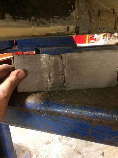1993 Ford Bronco - A metal bracket is being held in place for welding to a vehicle's frame.