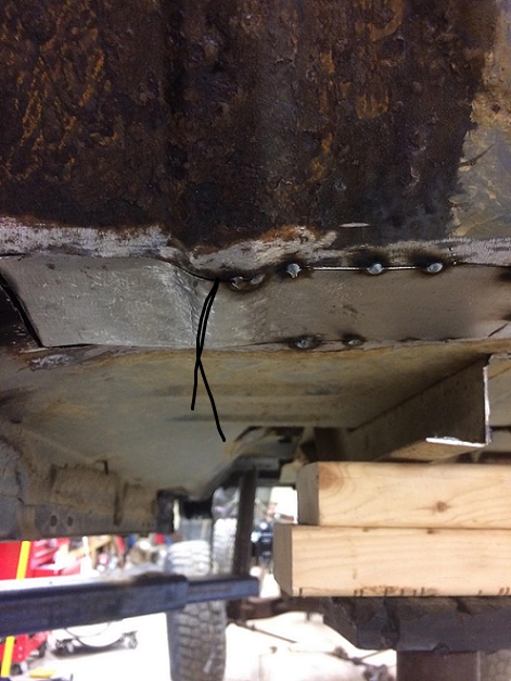 1993 Ford Bronco - Close-up view of vehicle underbody rust repair, showing welded seams and a piece of black string.
