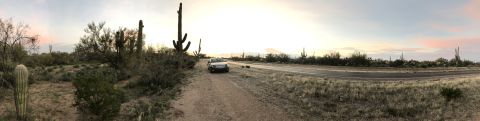 2007 Cadillac CTS - A solitary white sedan rests on a dusty track amidst the arid beauty of the desert, with saguaro cacti standing tall against the twilight s…