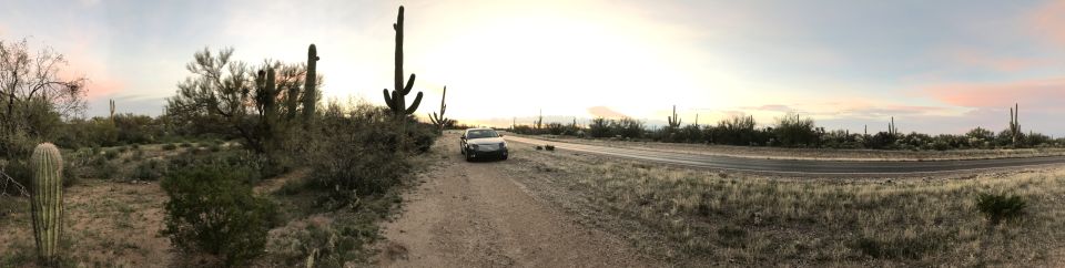 White sedan parked on a dirt road in a desert landscape with saguaro cacti