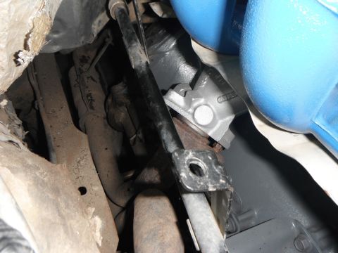 1995 Ford F-150 - A close-up view of the underside of a vehicle, showing various metal components, exhaust pipes, and a portion of a blue exhaust manifold or…