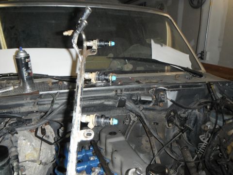 1995 Ford F-150 - The engine bay of a 1995 Ford F-150 shows a fuel rail with injectors and a can of spray cleaner. The vehicle is partially disassembled, wit…