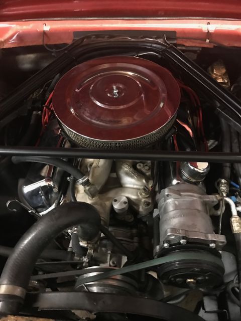 1965 Ford Mustang - A close-up view of a classic car engine bay, featuring a red air cleaner assembly and chrome accents. The image focuses on the engine compo…