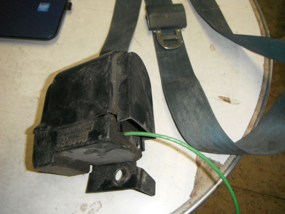Black seatbelt retractor with teal strap and green wire
