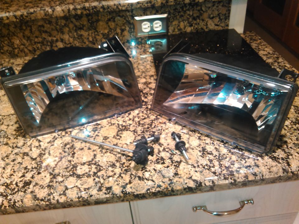 my current headlights are basically these same headlight housings are all chrome. they are the clear lenses with a little shroud to prevent hotspots. but them with 55w HID kits makes them amazing to drive with at night but super blinding to everybody else. figured it was try a projector retrofit kit.

because my dark green color of my truck i wanted to repalce the headlight housings with some darker headlights. they came with smoked turn signals not pictured. the headlight lenses are not smoked however.

first step was to separate the lenses from the housing. so i took the adjsuting hardware off jsut to prevent it from heat damage