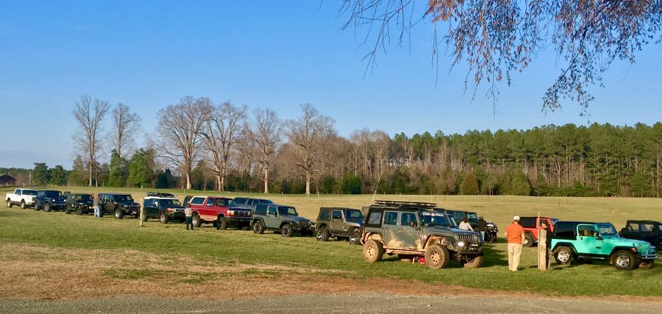 Line of off-road vehicles including Jeeps and a red Ford Bronco parked on a grassy field.