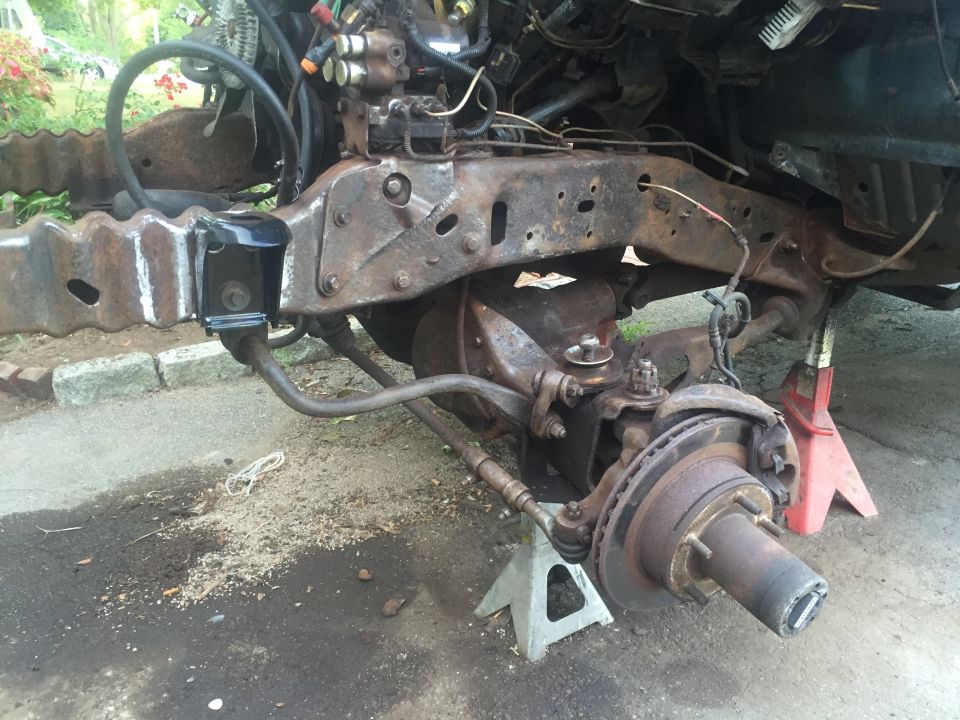 Vehicle frame and front suspension on jack stands. New black bracket installed.
