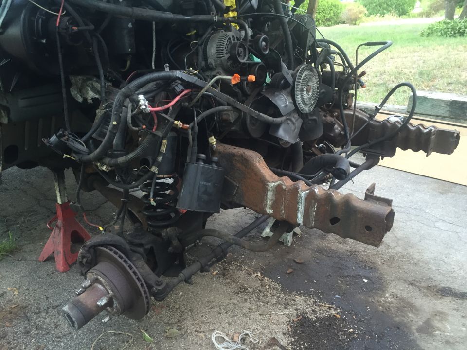 Disassembled 1995 Ford Bronco front chassis and engine on jack stands.