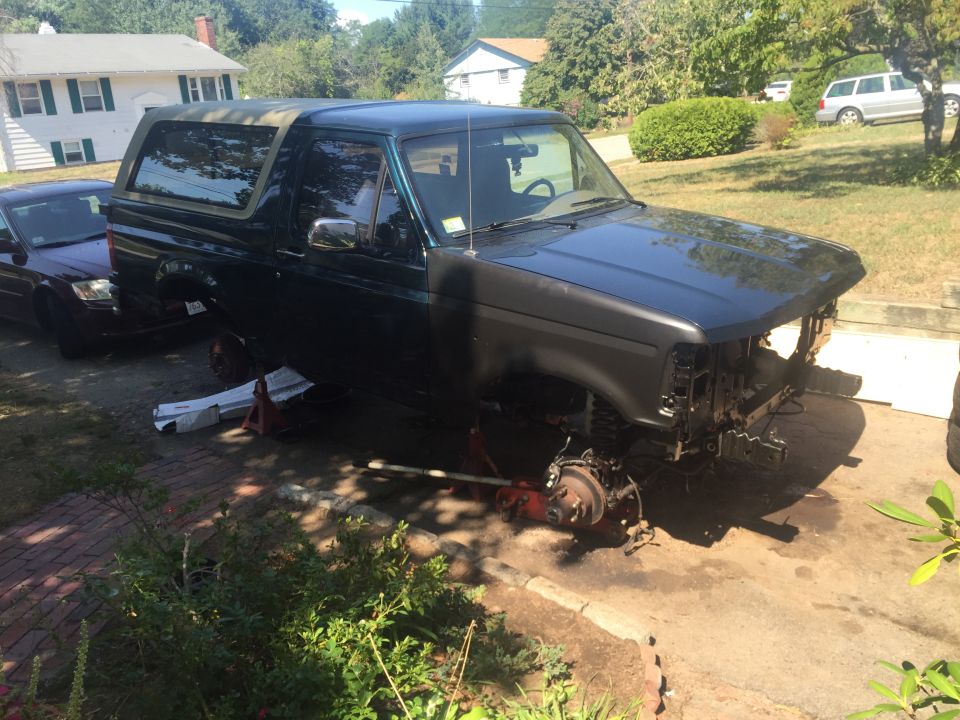 1995 Ford Bronco with front end disassembled, supported by jack stands.