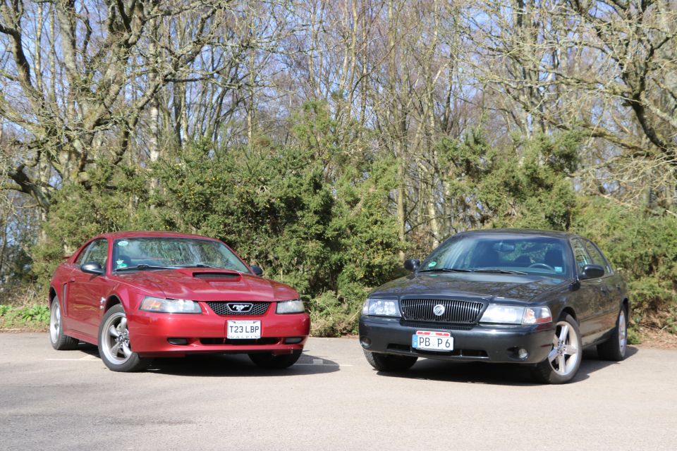Red Ford Mustang and black Mercury Marauder parked outdoors.